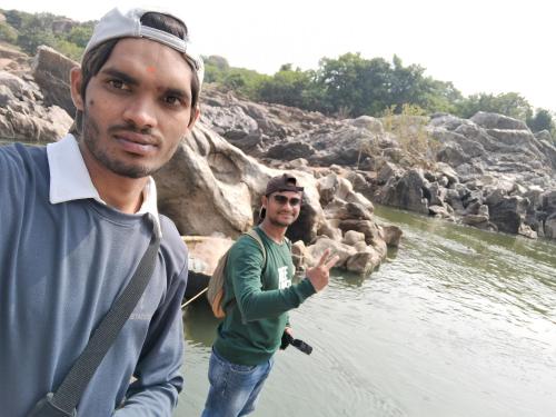two men standing in the water at a river at Lily Homestay in New Hampi