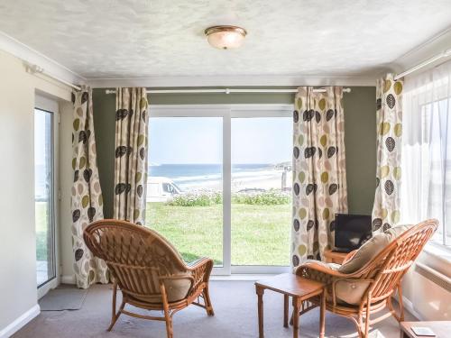 a living room with chairs and a large window at Apartment 1 Waterrs Edge in Crantock