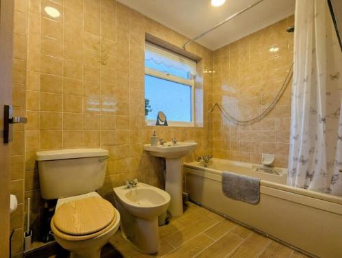 a bathroom with a toilet and a sink and a tub at Luxury 4BR Retreat, Garden, Parking, Modern Comfort in Balderton