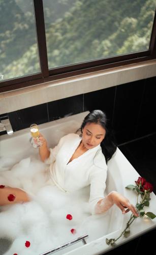 a woman laying in a bath tub with a glass of wine at Chandragiri Hills Resort Kathmandu-Luxury in the Clouds in Thānkot