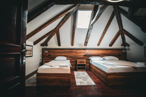 two beds in a room with wooden ceilings at Kuća za odmor Raguž in Andrijaševci