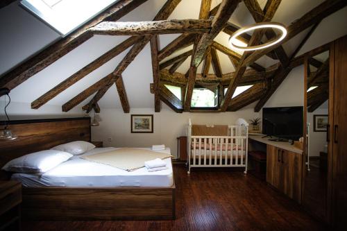 a bedroom with a bed and a tv and wooden ceilings at Kuća za odmor Raguž in Andrijaševci