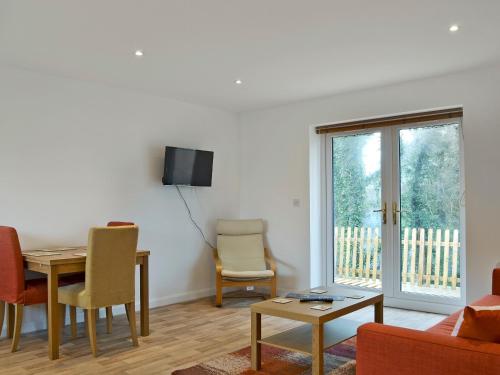 a living room with a table and chairs and a tv at Tawny Owls in Godstone