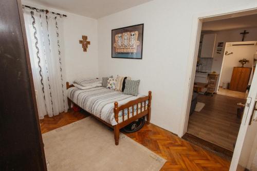 a small bed in a room with a cross on the wall at Urban Nest in Ljubuški