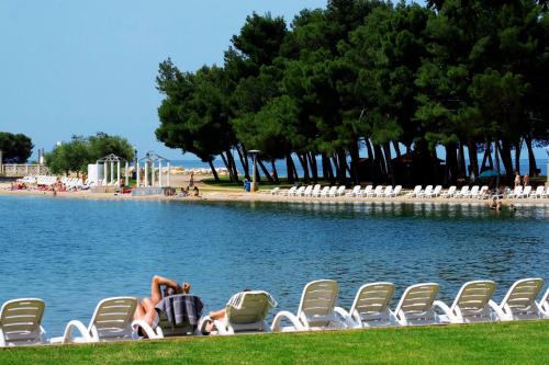 a group of chairs and people laying on the shore of a lake at Istrian Villas Plava Laguna in Umag