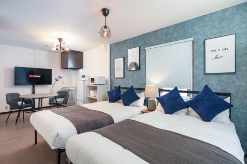 a hotel room with two beds and a dining room at Logements Tengachaya in Osaka