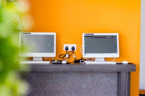 two computer monitors sitting on top of a desk at Big Orange Hotel Jitra in Alor Setar