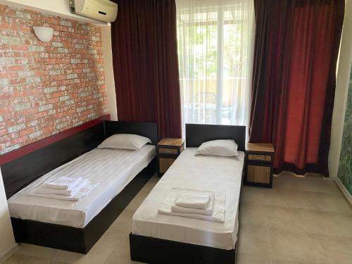 two beds in a room with a brick wall at Hotel Sea Star Приморско in Primorsko