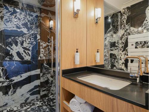 une salle de bain avec un lavabo et un grand miroir dans l'établissement Merveil Luxury Suite - Eiffel Tower terrasse, à Paris