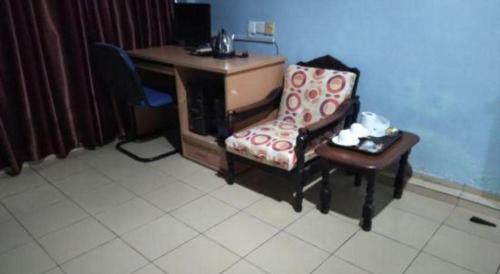a room with a desk and a chair next to a chair at OYO 90376 Centre Point Hotel in Limbang