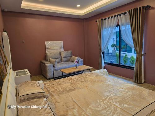 a bedroom with a large bed and a chair at My Paradise Chiang Rai in Ban Doi Hang