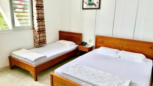 a bedroom with two beds and a window at Hà Tiên Hạnh Phúc Hotel in Ha Tien