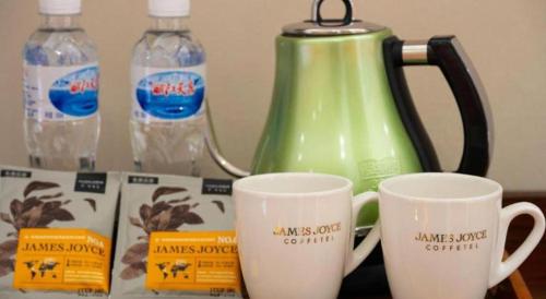 two coffee mugs sitting on a table with bottles of water at James Joyce Coffetel·Lijiang Old Town Centeral in Lijiang
