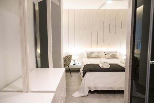 a white bedroom with a bed and a chair at AvantiStays Porta Coeli con PARKING GRATIS in Sanlúcar de Barrameda