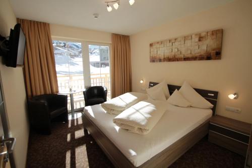 Habitación de hotel con cama con almohadas blancas en Appartements Andy, en Obergurgl