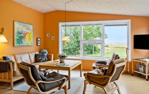 Sønder YdbyにあるStunning Home In Hurup Thy With Wifiのオレンジ色の壁とテーブルと椅子のあるリビングルーム