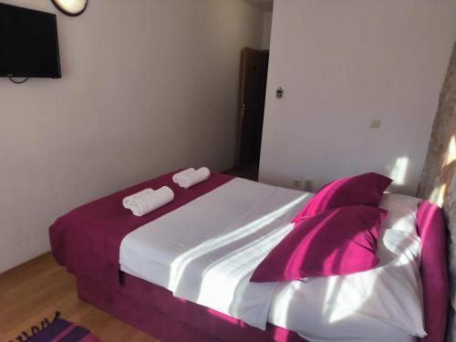 a bedroom with a bed with purple and white sheets and pillows at Omir Bed & Breakfast in Pula