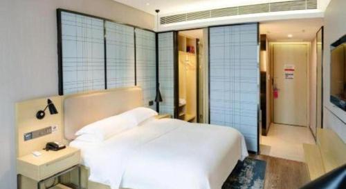 a bedroom with a large white bed and a bathroom at Echarm Hotel Xiangyang Erqi in Xiangyang
