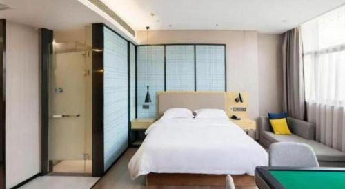 a bedroom with a large white bed and a window at Echarm Hotel Xiangyang Erqi in Xiangyang