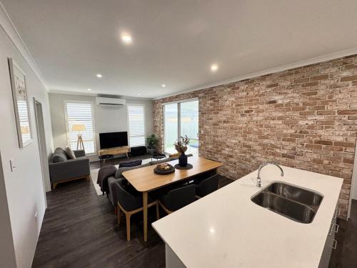 a kitchen and living room with a brick wall at Georgette Retreat in Busselton