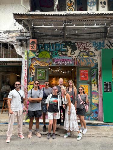 a group of people standing in front of a building with graffiti at Here We Go Bangkok in Bangkok