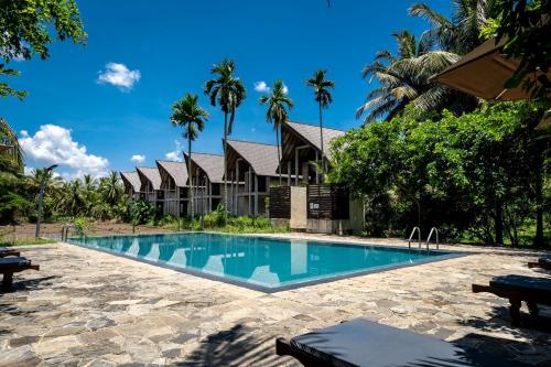 a swimming pool in front of a house with palm trees at Lavendish Wild Wilpattu in Nochchiyagama