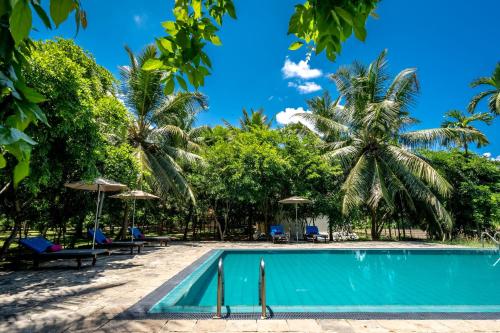 a swimming pool in front of a resort with palm trees at Lavendish Wild Wilpattu in Nochchiyagama