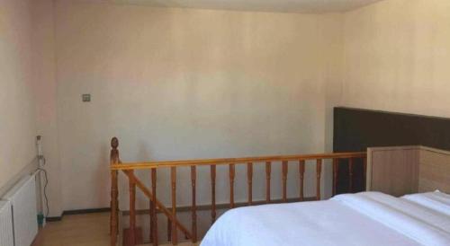 a bedroom with a bed and a wooden railing at 7 Days Inn Zhangjiakou Chongli Yuxing Road in Zhangjiakou