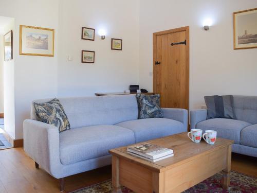 un salon avec un canapé bleu et une table basse dans l'établissement Barn Cottage, à Talley