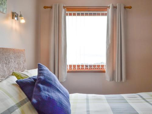 a bedroom with a window and a bed with blue pillows at Bayview - Uk32931 in Gairloch