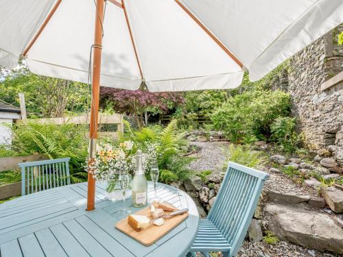 a table with an umbrella in a garden at Pier Haven - Cottage in Blairmore