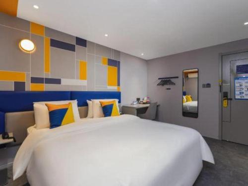 a bedroom with a large white bed with yellow and blue pillows at 7 Days Inn Nanjing Xinjiekou Changfu Street Metro Station in Nanjing