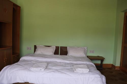 a bed with white sheets and towels on it at Nilza Guest House in Leh