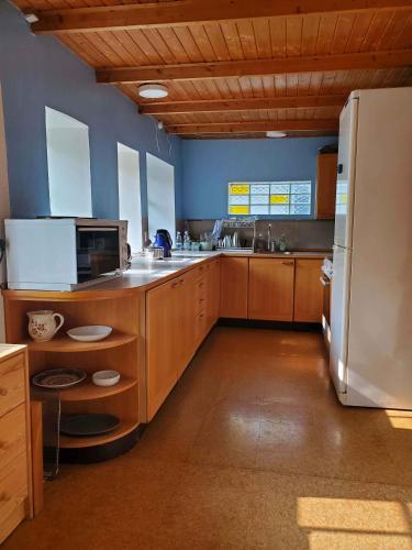 a large kitchen with wooden cabinets and a refrigerator at Charming Farmhouse With Room For 8 in Søllested