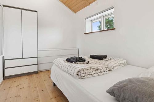 a white bedroom with a bed and a mirror at Apartment In Snogebæk Near The Beach in Neksø