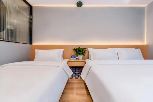 two beds in a room with a table between them at Aimoke hotel in Chongqing