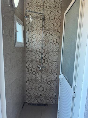 a shower in a bathroom with a tile wall at Villa Luna in Hanshīr Qaşr Ghallāb