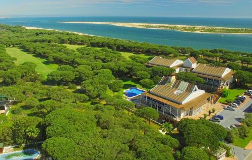 una vista aérea de una casa con árboles y el océano en Hotel Nuevo Portil Golf, en El Rompido