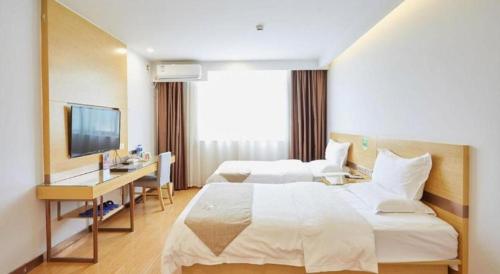 a hotel room with two beds and a desk and a television at GreenTree Inn Huayin Huashan Town Huashan Scenicspot Express Hotel in Huayin