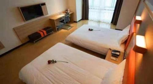a hotel room with two beds and a television at 7 Days Premium Yancheng Dafeng Zhongjiao Meilu City in Yancheng