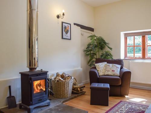 ein Wohnzimmer mit einem Holzofen und einem Stuhl in der Unterkunft Dairy Cottage in Talley
