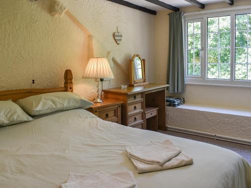 a bedroom with a bed with a mirror and a window at Uk40278 - Llys Elen One in Brynsiencyn