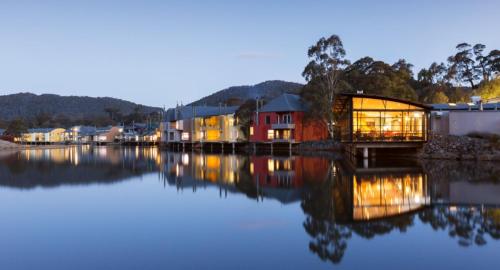 a house on the water next to a river at Oaks Lake Crackenback Resort in Crackenback