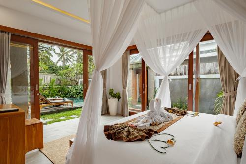 a bedroom with a bed with a white canopy at Badawa Ubud Villa in Ubud