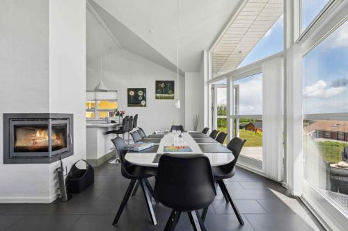 a dining room with a long table and a fireplace at Sea View And Calm In Lovely House For 10 Guests in Augustenborg