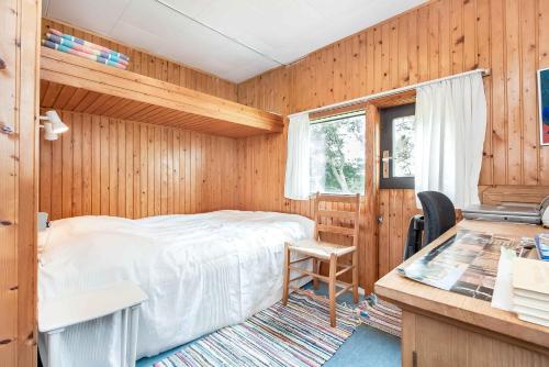 une chambre avec un lit dans une pièce en bois dans l'établissement Lovely Cottage Close To The North Sea, à Pandrup
