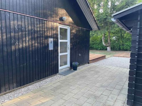 a black building with a door and a patio at Cozy And Child-Friendly Holiday Home In Arrild in Toftlund