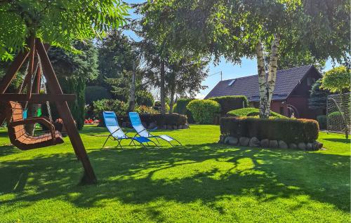 two blue chairs in a yard with a swing at Stunning Home In Cieciorka in Cieciorka