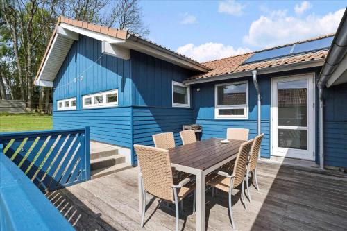 a blue house with a table and chairs on a deck at Beach, Starry Sky And Peace By The Water in Augustenborg