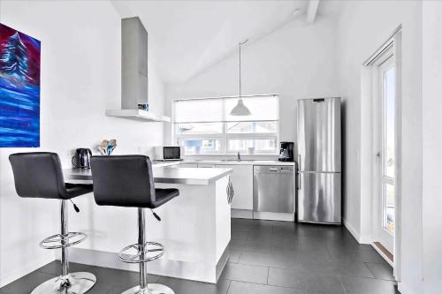 a white kitchen with two bar stools and a refrigerator at Beach, Starry Sky And Peace By The Water in Augustenborg